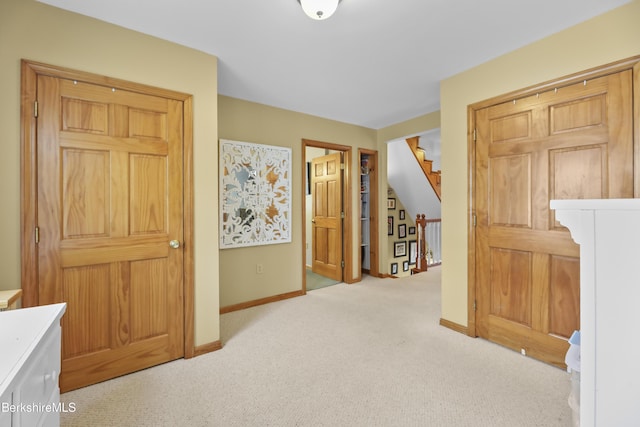 corridor with stairs, baseboards, and light carpet