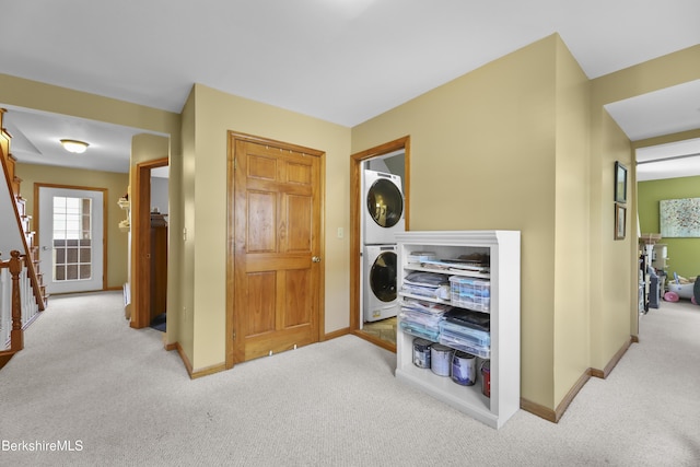 laundry room featuring laundry area, baseboards, carpet, and stacked washer / drying machine