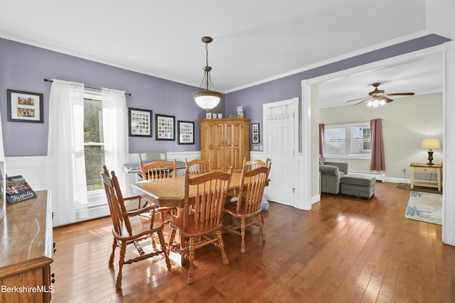 dining space with crown molding, baseboards, ceiling fan, and hardwood / wood-style flooring