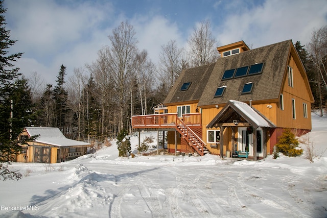 snow covered back of property with a deck