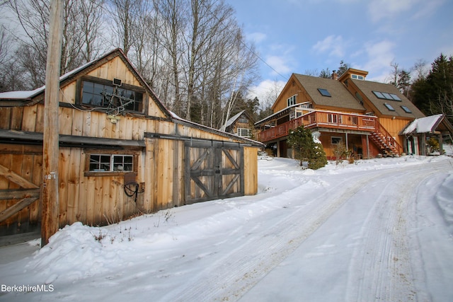 view of snowy exterior featuring an outbuilding and a wooden deck