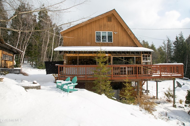 snow covered back of property featuring a wooden deck