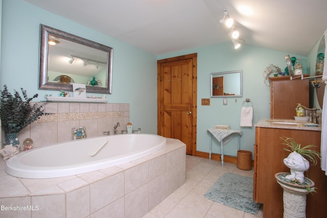 bathroom featuring a relaxing tiled tub, tile patterned floors, lofted ceiling, and vanity