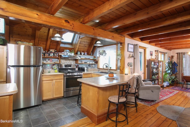 kitchen with sink, appliances with stainless steel finishes, beam ceiling, a kitchen breakfast bar, and decorative light fixtures