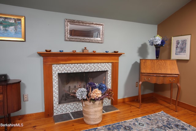 interior space featuring a tile fireplace, lofted ceiling, and light wood-type flooring