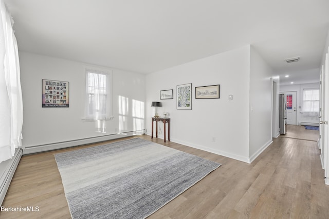 unfurnished room featuring a baseboard radiator and light hardwood / wood-style flooring