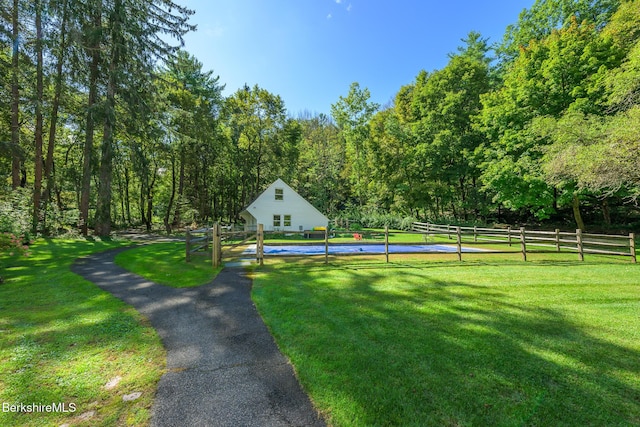 surrounding community featuring a yard, a forest view, and fence
