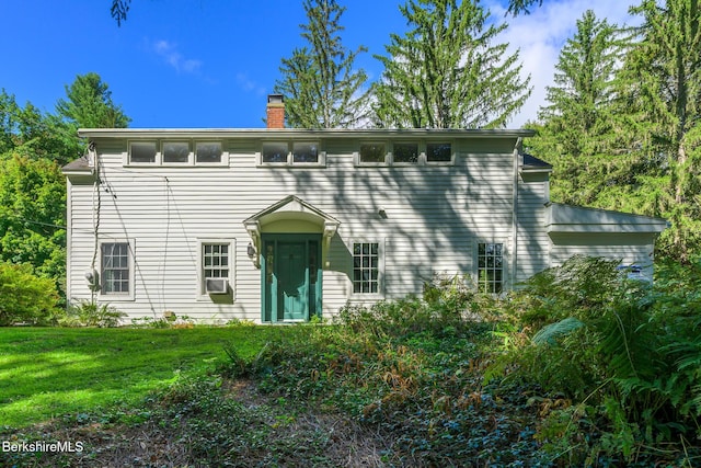 colonial home with a chimney and a front yard