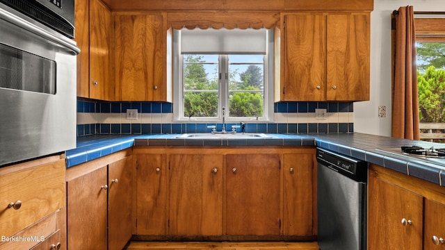 33 Quirico Dr, Pittsfield, MA 01201 - kitchen featuring appliances with stainless steel finishes, tile counters, brown cabinets, and tasteful backsplash