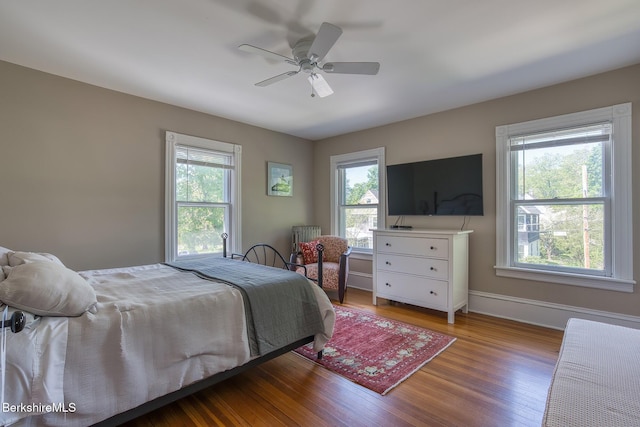 bedroom with multiple windows, wood finished floors, baseboards, and a ceiling fan