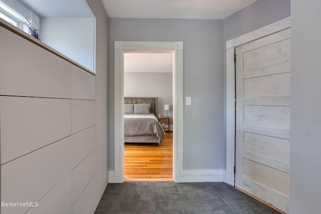 corridor featuring dark carpet and baseboards
