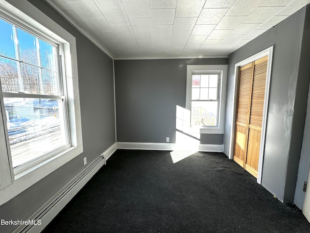 spare room with dark colored carpet and baseboard heating