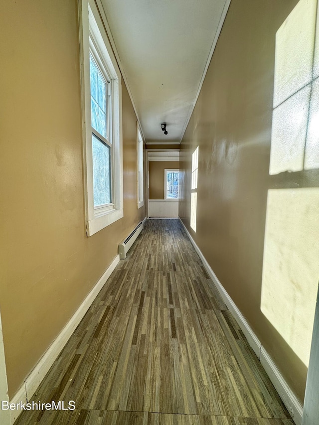 hall with a baseboard heating unit, crown molding, and hardwood / wood-style flooring