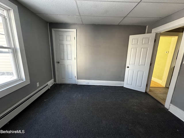 carpeted spare room featuring a drop ceiling and baseboard heating