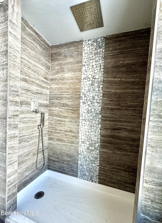 bathroom with a tile shower and a textured ceiling