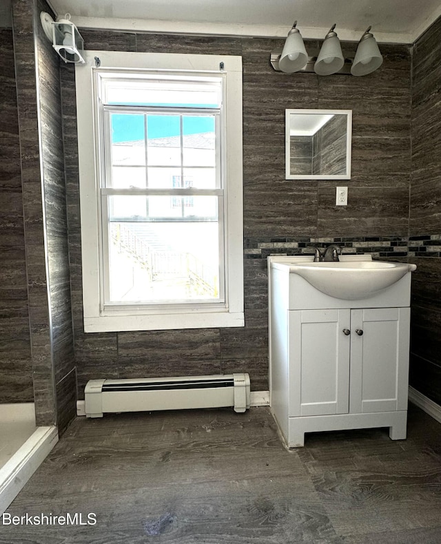 bathroom featuring vanity, a baseboard heating unit, wood-type flooring, and a shower