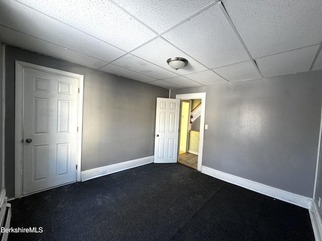 interior space featuring dark carpet and a drop ceiling