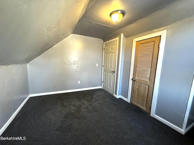 additional living space featuring dark colored carpet and lofted ceiling