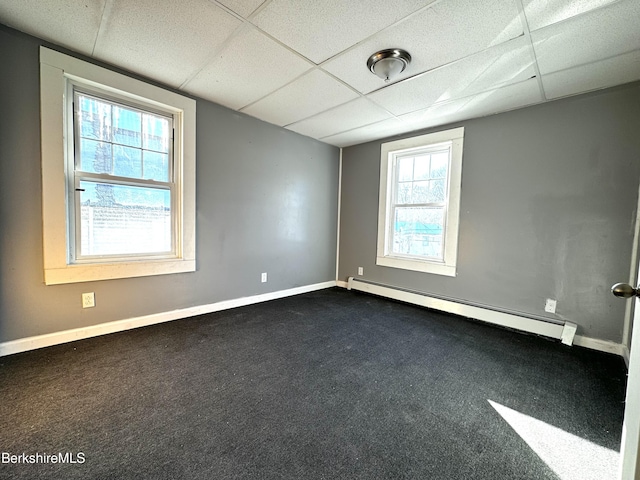 empty room featuring dark carpet, a paneled ceiling, and baseboard heating