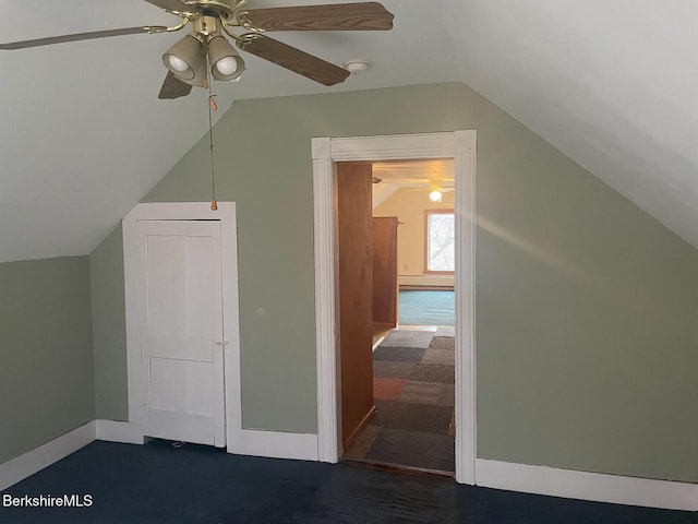 bonus room with dark carpet, vaulted ceiling, and ceiling fan