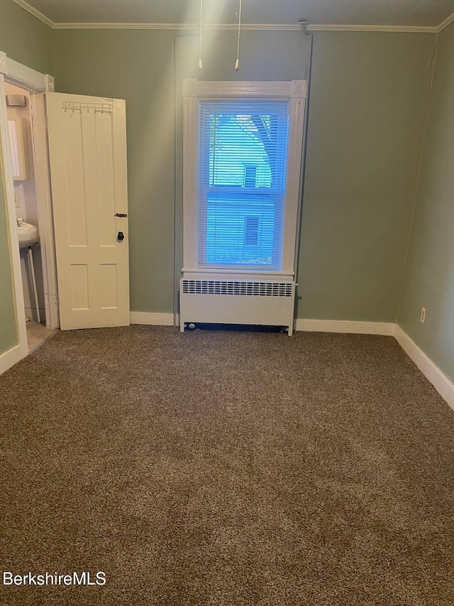 spare room featuring carpet, radiator heating unit, and crown molding