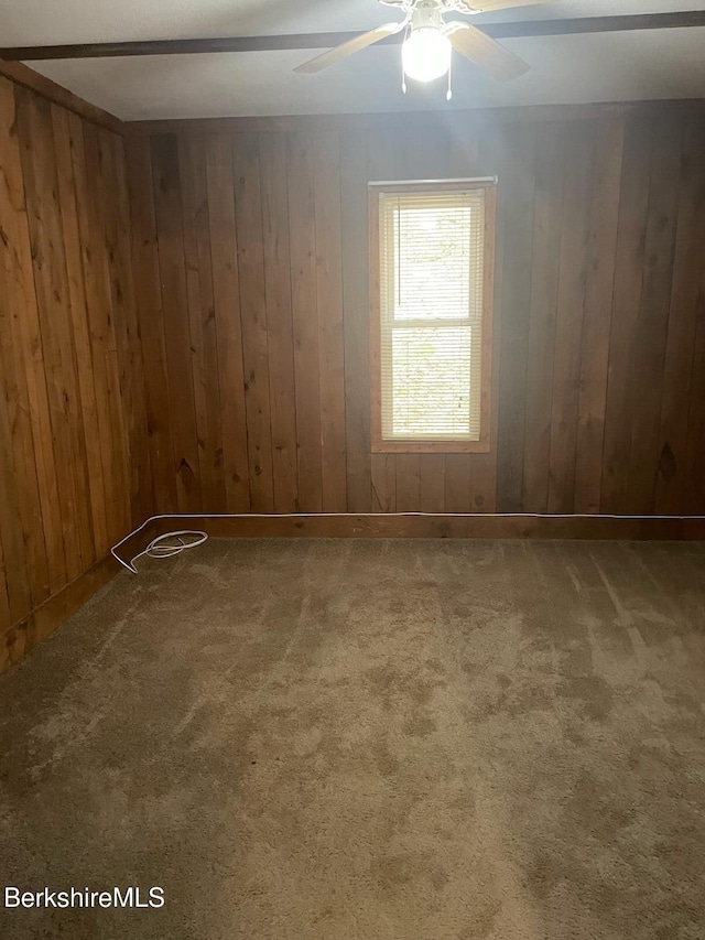 unfurnished room featuring carpet flooring, ceiling fan, and wooden walls