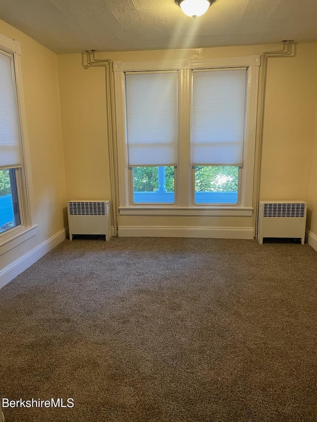 carpeted spare room with radiator heating unit and a textured ceiling