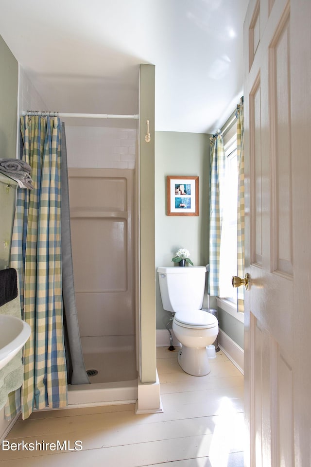 bathroom with hardwood / wood-style flooring, toilet, and walk in shower