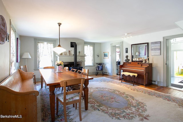 dining room with wood-type flooring, a baseboard radiator, and a wood stove