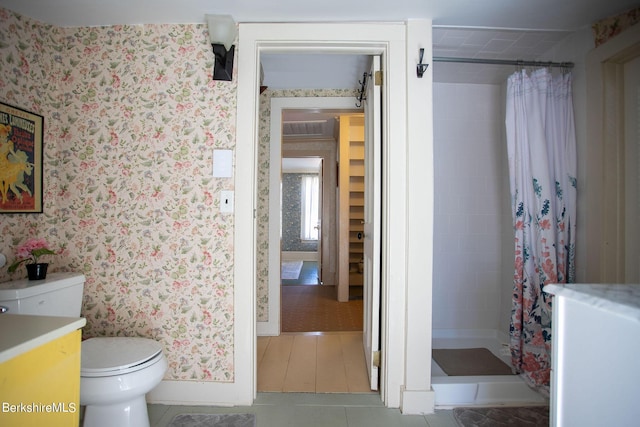 bathroom with tile patterned flooring, vanity, toilet, and curtained shower