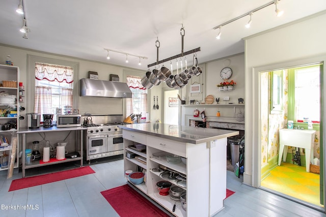 kitchen featuring stainless steel counters, plenty of natural light, wall chimney range hood, and appliances with stainless steel finishes