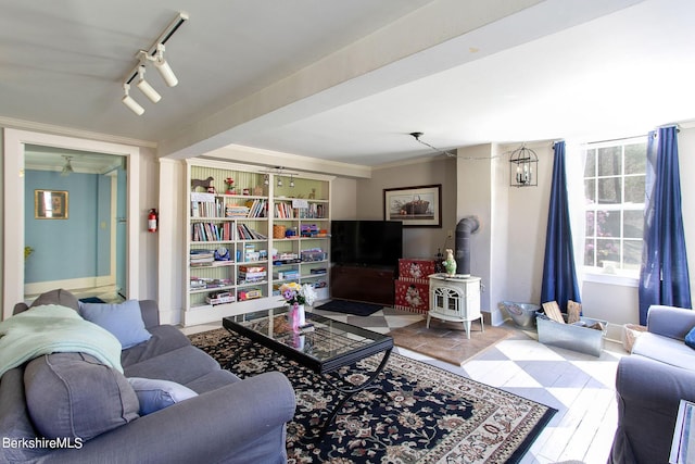 living room featuring track lighting, a wood stove, and crown molding