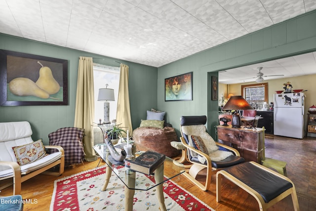 sitting room featuring wood finished floors, a healthy amount of sunlight, and ceiling fan