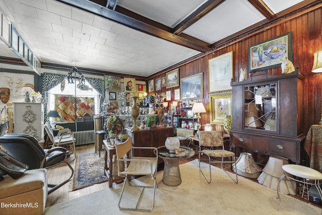 living area with beamed ceiling, radiator, and wooden walls