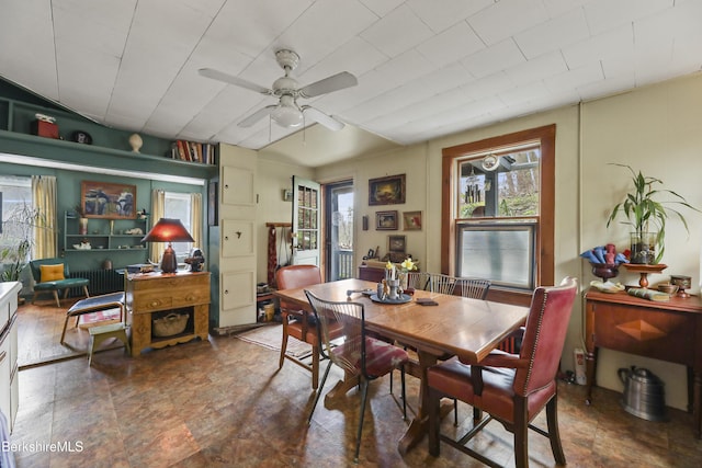 dining room featuring stone finish flooring, radiator, and ceiling fan