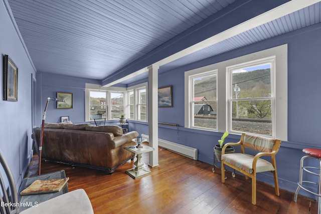 living room with a healthy amount of sunlight, a baseboard heating unit, and hardwood / wood-style floors