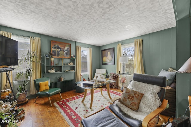 sitting room with hardwood / wood-style floors, radiator heating unit, and a healthy amount of sunlight