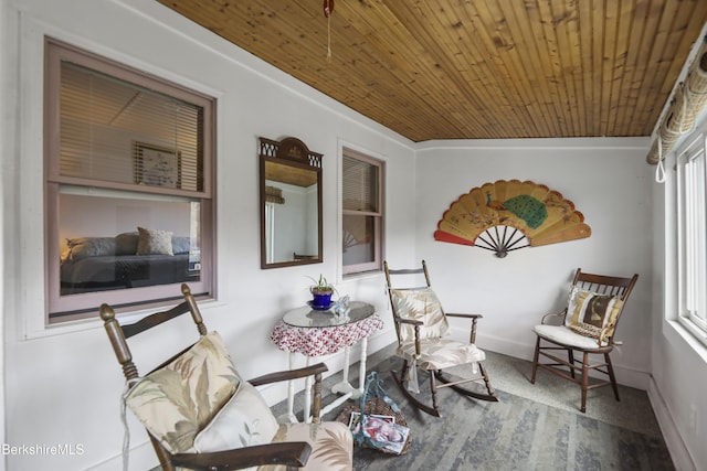 living area featuring baseboards, wood finished floors, and wood ceiling