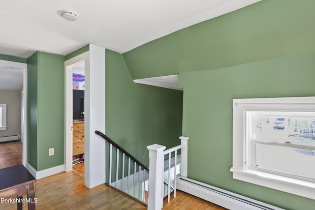 staircase with a baseboard heating unit and hardwood / wood-style floors