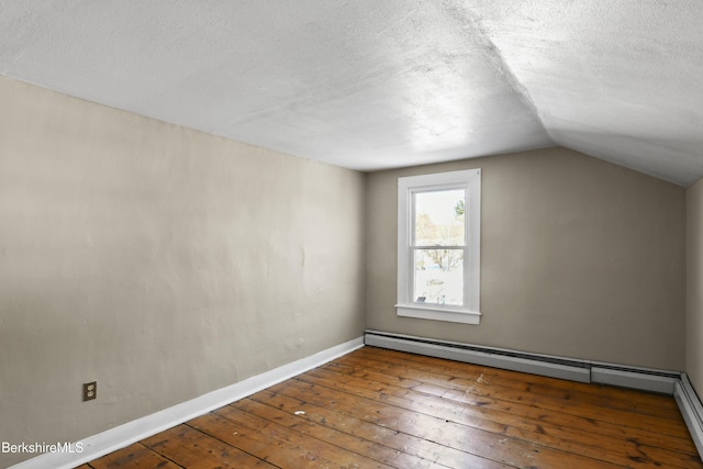 additional living space with baseboard heating, wood-type flooring, vaulted ceiling, and a textured ceiling