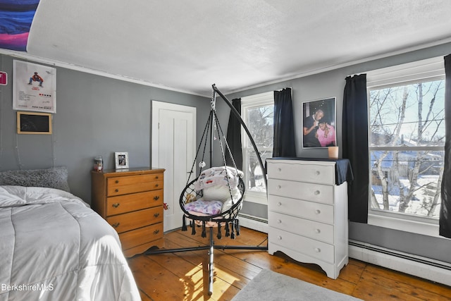 bedroom with hardwood / wood-style flooring and a baseboard radiator