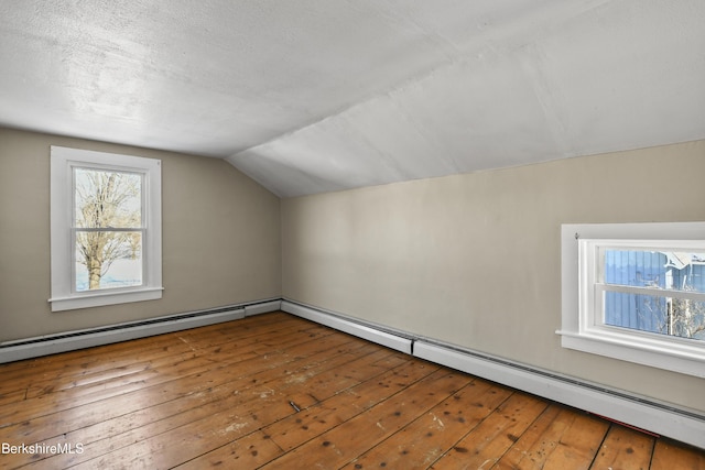 additional living space featuring lofted ceiling, hardwood / wood-style floors, a baseboard radiator, and a textured ceiling