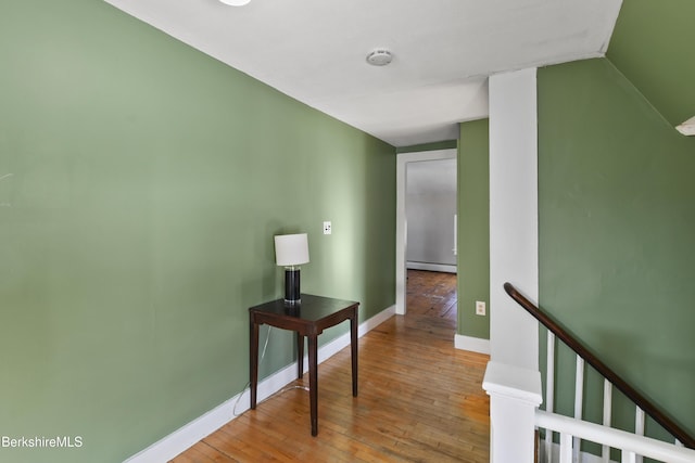 corridor with a baseboard radiator and light hardwood / wood-style flooring