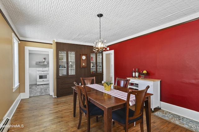 dining room featuring a notable chandelier, crown molding, dark wood-type flooring, and baseboard heating