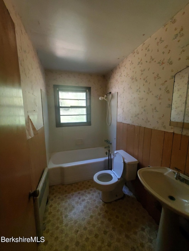 bathroom featuring radiator, wood walls, shower / washtub combination, and toilet