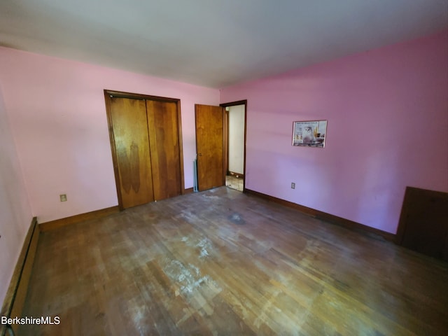 unfurnished bedroom with dark wood-type flooring and a baseboard heating unit