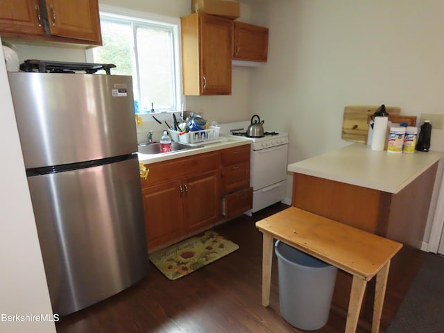 kitchen featuring stainless steel fridge, dark hardwood / wood-style flooring, white range with gas cooktop, and sink