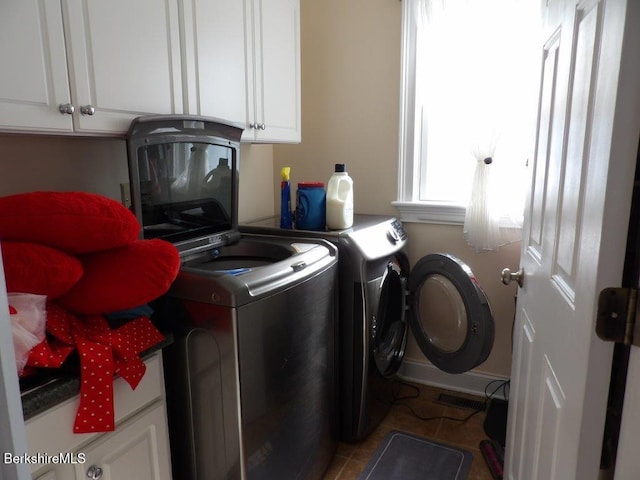 laundry room featuring a garage, independent washer and dryer, cabinet space, and tile patterned floors