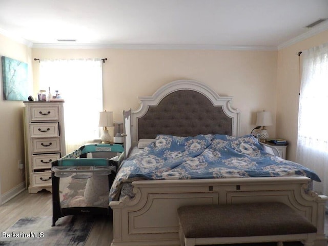 bedroom featuring light wood-type flooring, multiple windows, visible vents, and ornamental molding