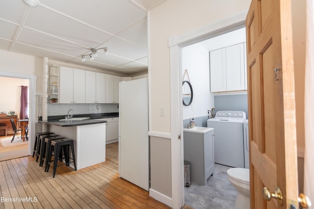 interior space featuring cabinets, washer and clothes dryer, sink, and light wood-type flooring